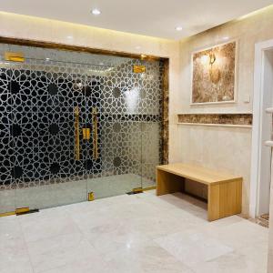 a bathroom with a shower and a wooden bench at أجنحة هدوء وصول ذاتي in Al Madinah