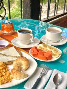 une table avec des assiettes de nourriture et des tasses de café dans l'établissement Oak Tree house, à Guatapé