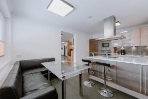 a living room with a black leather couch and a kitchen at Appartement Sporthütte Fiegl in Sölden