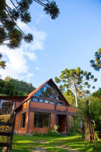 una casa de ladrillo con ventanas de cristal y un árbol en Oca Roça, en Delfim Moreira