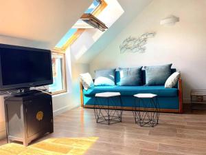 a living room with a blue couch and a tv at Duplex Bord De Mer in Le Croisic