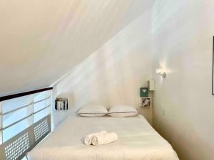 a white bedroom with a bed with towels on it at Duplex Bord De Mer in Le Croisic
