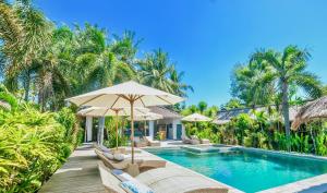 een zwembad van het resort met stoelen en parasols bij L'Archipel in Gili Air