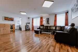 a living room with a black leather couch and wooden floors at Appartement Sporthütte Fiegl in Sölden