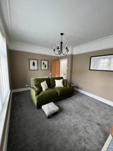 a living room with a green couch and a window at Cottage in Whalley in Whalley