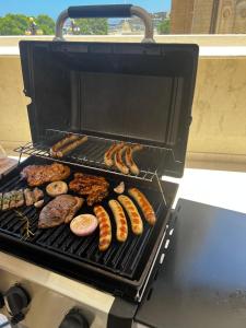 a grill with different types of meat and sausages at The White Knight Premium Boutique Hotel in Għajnsielem