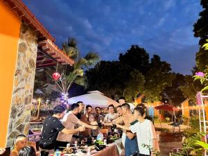Homestay Bài Văn garden في بافي: مجموعة من الناس تقف حول طاولة مع الطعام