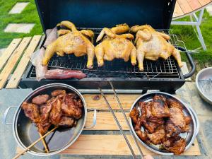 Drei Hühner und Fleisch kochen auf einem Grill in der Unterkunft Homestay Bài Văn garden in Ba Vì