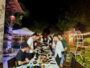 a group of people standing around a table with food at Homestay Bài Văn garden in Ba Vì