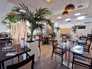 a restaurant with tables and chairs and a potted plant at Hôtel de La Poste in La Cavalerie