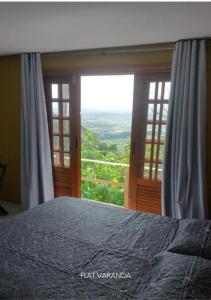 a bedroom with a bed and a large window at Refúgio Serra Negra - PE in Bezerros