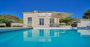 a villa with a swimming pool and an umbrella at Villa bleu Tropez in Gassin