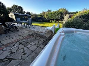 einen Whirlpool im Hinterhof mit einem Tisch und Stühlen in der Unterkunft Kennedy Villa - 5 Bed House with Hot Tub in Bicester