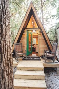 una cabaña en el bosque con dos sillas y una puerta verde en The Green Glamping Getaway, en Rockbridge