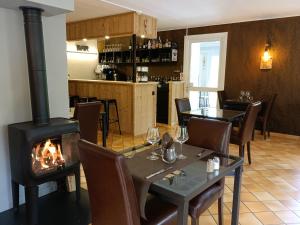 a fireplace in a restaurant with a table and a stove at Hôtel Le Martagon in Villars-Colmars