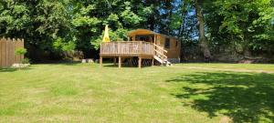 une cabane en bois dans une cour avec une pelouse dans l'établissement Roulotte Escapade nature à Morainville, à Morainville-près-Lieurey