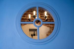 a window in a blue wall with a mirror at SĪMANIS Boutique Hotel in Kuldīga