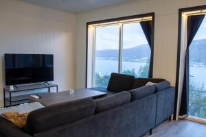 a living room with a couch and a large window at Modern Fjord View Apartment in Tromsø