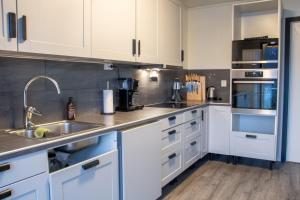 a kitchen with white cabinets and a sink at Modern Fjord View Apartment in Tromsø