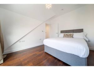 a bedroom with a large white bed and a staircase at Gwel An Keynvor Penthouse in Newquay
