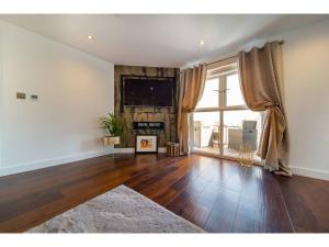 a living room with wooden floors and a large window at Gwel An Keynvor Penthouse in Newquay