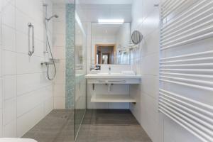 bagno bianco con lavandino e doccia di Alpine Club Resort a Schladming