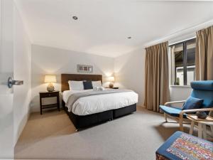 a bedroom with a bed and a blue chair at Townhouse 212 in Margaret River Town