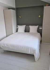 uma grande cama branca com lençóis e almofadas brancos em Victoire Opale 202 climatisé hôtel de ville em Saint-Dizier
