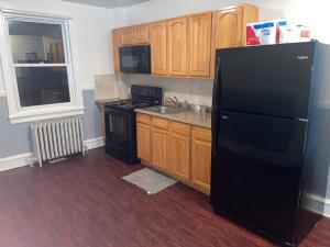 a kitchen with a black refrigerator and wooden cabinets at Nice and quiet appartement in Philadelphia