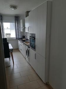 uma cozinha com armários brancos e uma máquina de lavar e secar roupa em Ferienwohnung Michelle em Bremerhaven
