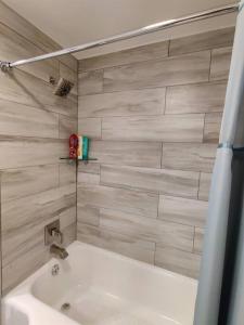 a white bath tub in a bathroom with a tile wall at Door County Cottage, near Haines Beach! in Sturgeon Bay