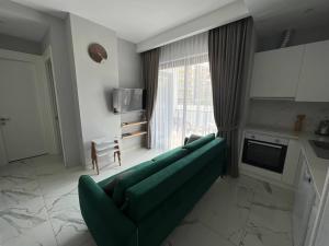 a living room with a green couch in front of a window at The Yacht apartments in Alanya