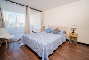 a bedroom with a bed and a large window at Lindo departamento amoblado en Cavancha. in Iquique