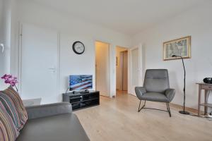 ein Wohnzimmer mit einem Sofa, einem Stuhl und einer Uhr in der Unterkunft Carpe Diem Carpe Diem Appartement 161 in Niendorf