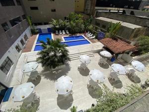 an overhead view of a patio with umbrellas and a pool at Apartamento dois dormitórios Praia das Pitangueiras in Guarujá