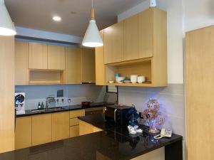 a kitchen with wooden cabinets and a black counter top at The Floorspace Imperial Suites Apartment in Kuching