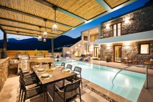 an indoor pool with a table and chairs next to a house at Mirthea Suites in Mírthios