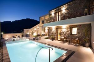 a villa with a swimming pool at night at Mirthea Suites in Myrthios
