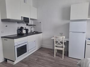 een keuken met witte apparatuur en een tafel en een stoel bij Studio Apartment 8 in Essen