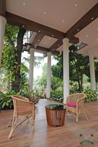 two chairs and a table on a porch with trees at Serenity Villa and Treehouse in Palakkad