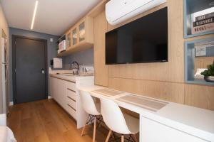 a kitchen with a desk with a tv on the wall at Luxuoso Studio BF - CWB Central in Curitiba