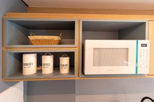 a microwave and four coffee mugs in a cabinet at 1306 - Luxuoso Studio BF - CWB Central - Com Garagem in Curitiba