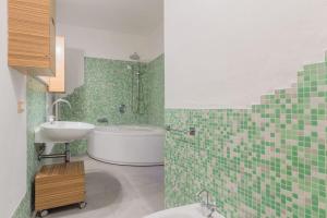 a green tiled bathroom with a tub and a sink at Appartamento a Piacenza in Piacenza