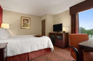 a hotel room with a bed and a flat screen tv at Hampton Inn Magnolia in Magnolia