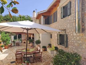 une terrasse avec une table et un parasol en face d'un bâtiment dans l'établissement La casa di Bella a tradional stone house with barbecue, à Kariá