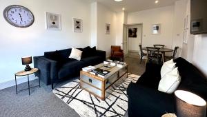 una sala de estar con sofás y un reloj en la pared en Stylish 3Bed apartment with FREE PARKING en Heaton