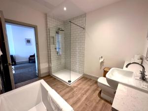 a bathroom with a shower and a tub and a sink at Stylish 3Bed apartment with FREE PARKING in Heaton