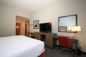 a hotel room with a bed and a desk with a television at Hampton Inn Bordentown in Bordentown
