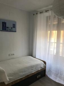 um quarto com uma cama e uma janela com cortinas brancas em WADI DAR AL-FARAH, ( LA CASA DE LA ALEGRIA DE GUADIX) em Guadix