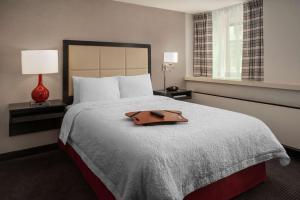 a hotel room with a bed with a brown purse on it at Hampton Inn & Suites Milwaukee Downtown in Milwaukee